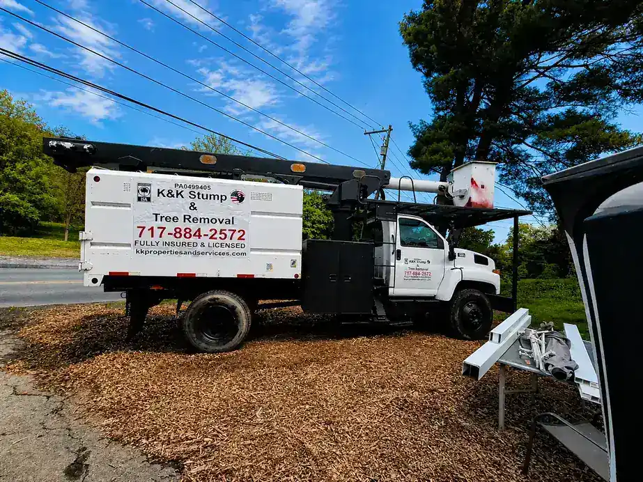 K&K's white bucket and chip truck parked on a bed of wood chips beside the road